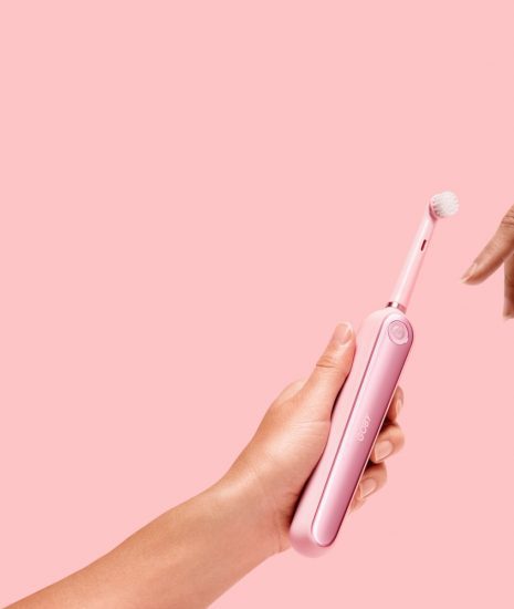 person holding pink electric toothbrush