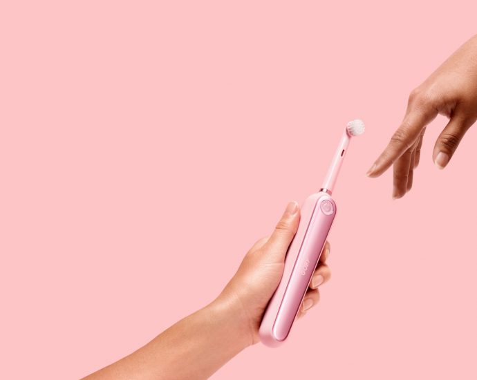 person holding pink electric toothbrush