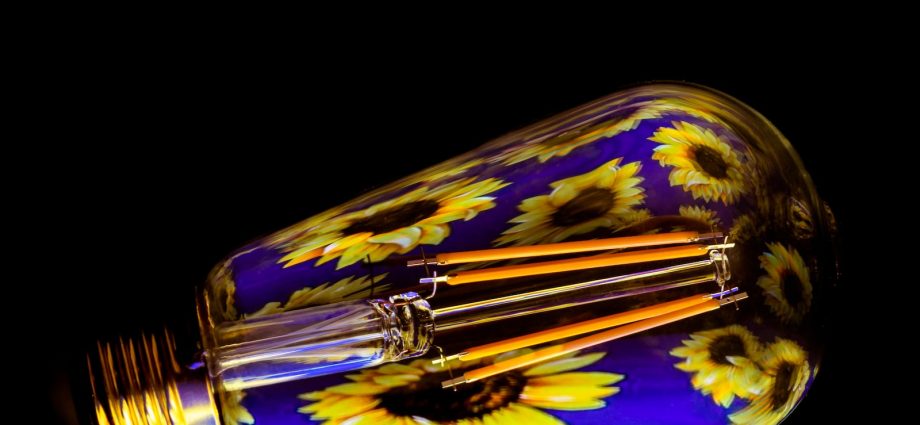 a yellow and blue glass light bulb on a black background